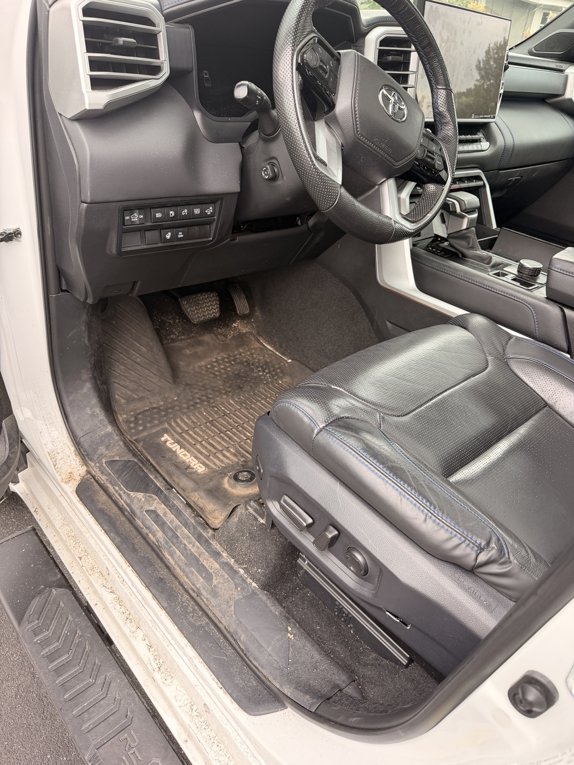 Toyota Tundra driver’s seat, floor mat, and door sill before detailing, with visible dirt and debris.